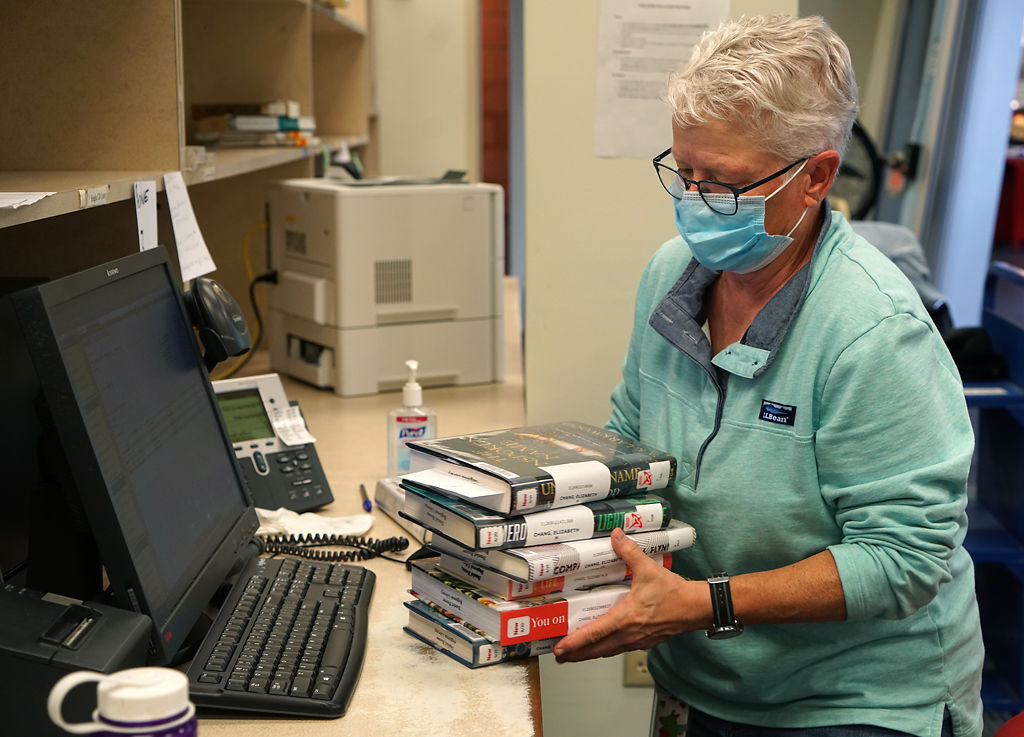 Jill Mackey holds six books and prepares to check out